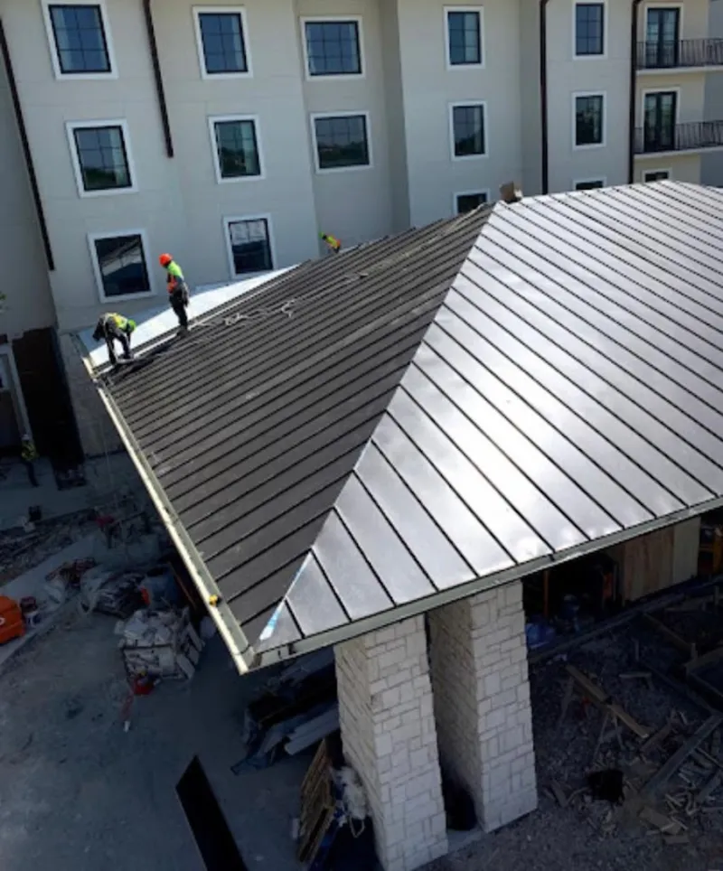 Crew installing standing seam metal roof panels on a commercial project in Endicott